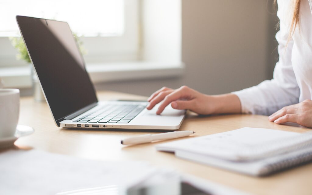 Donna che segue un corso online con il computer aperto e un quaderno