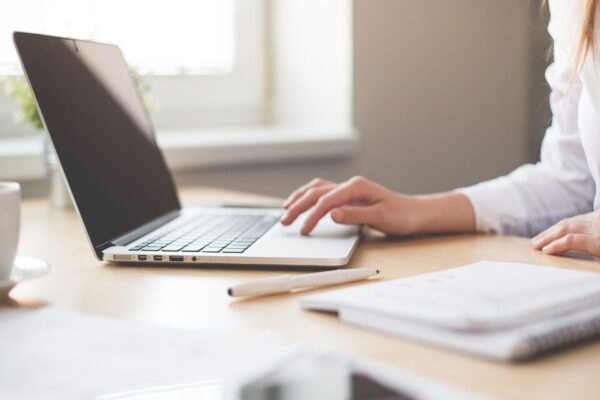 Donna che segue un corso online con il computer aperto e un quaderno